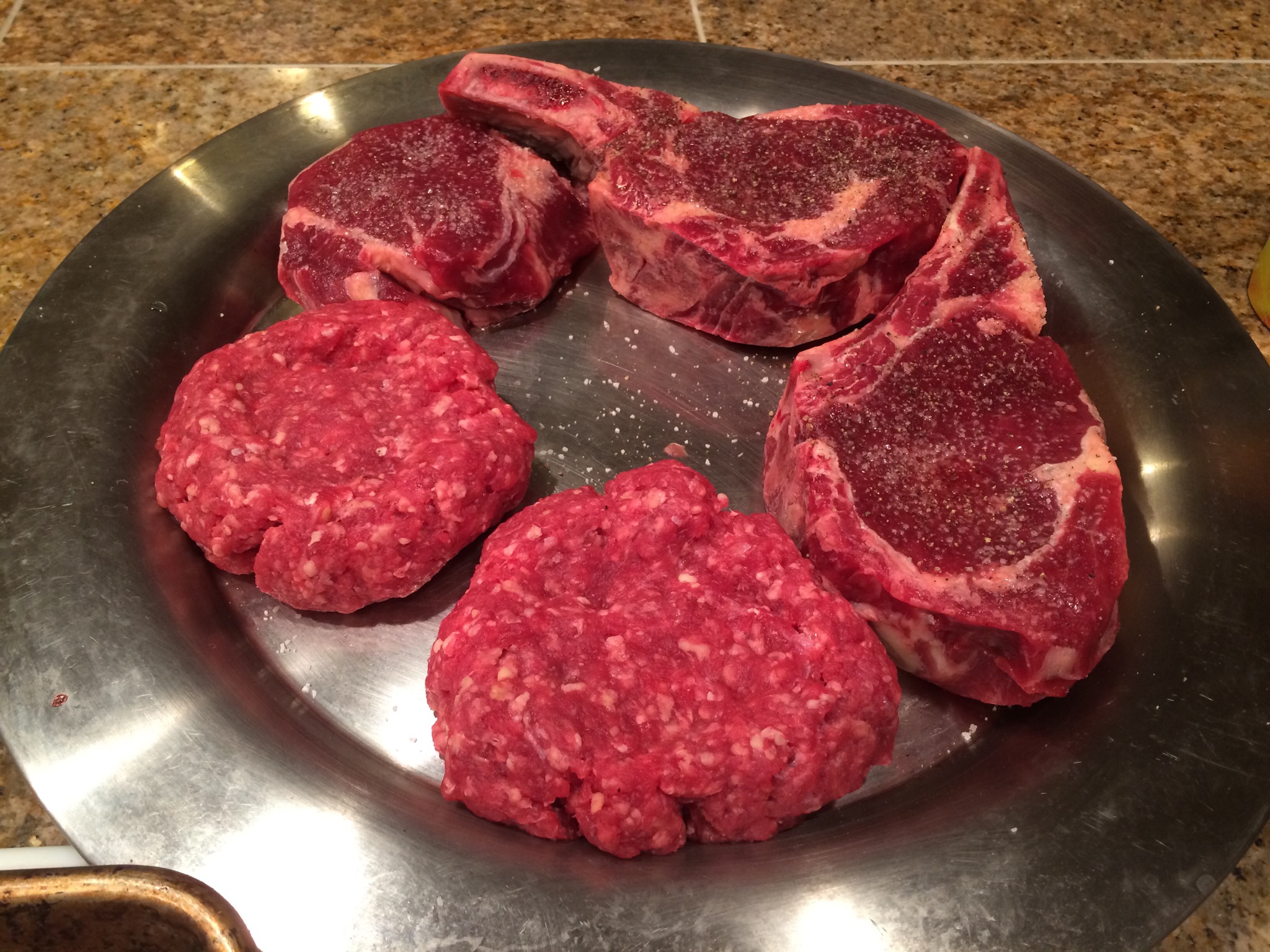 Steaks and burgers on the platter, ready to go on the fire.