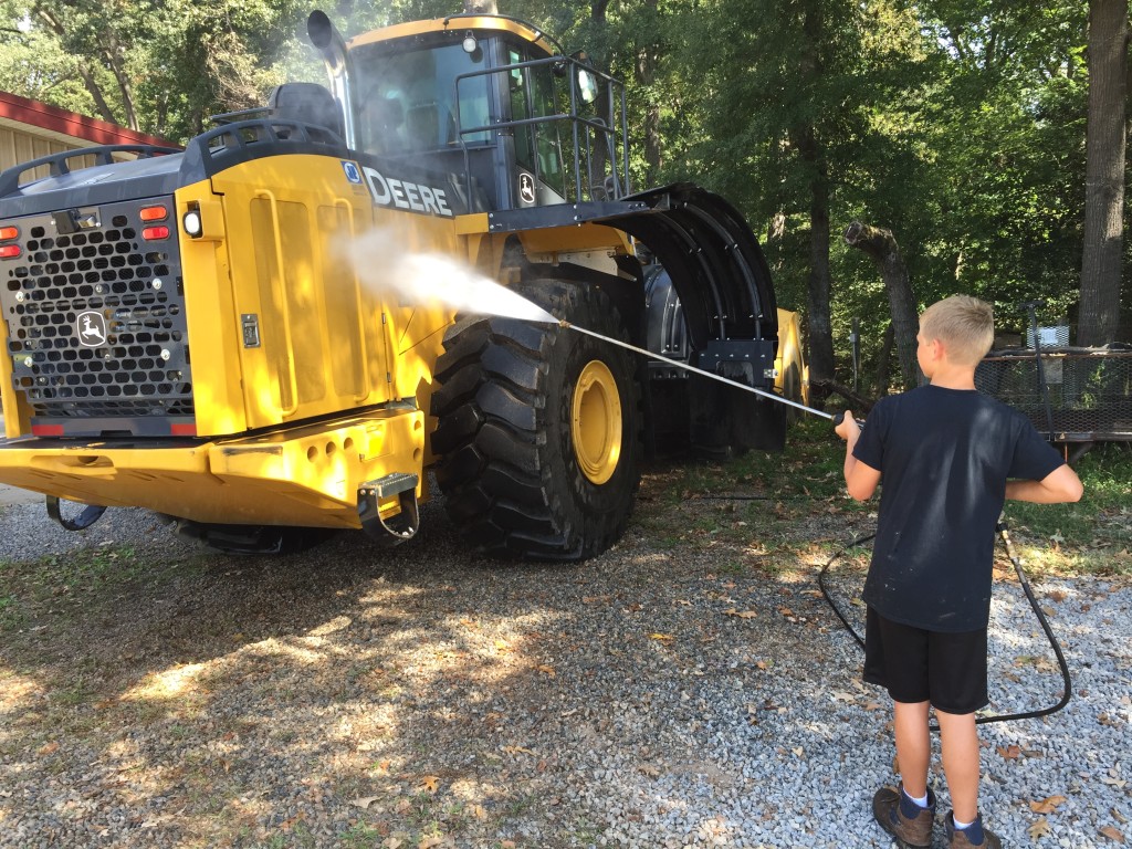 Boy powerwashing a huge tractor