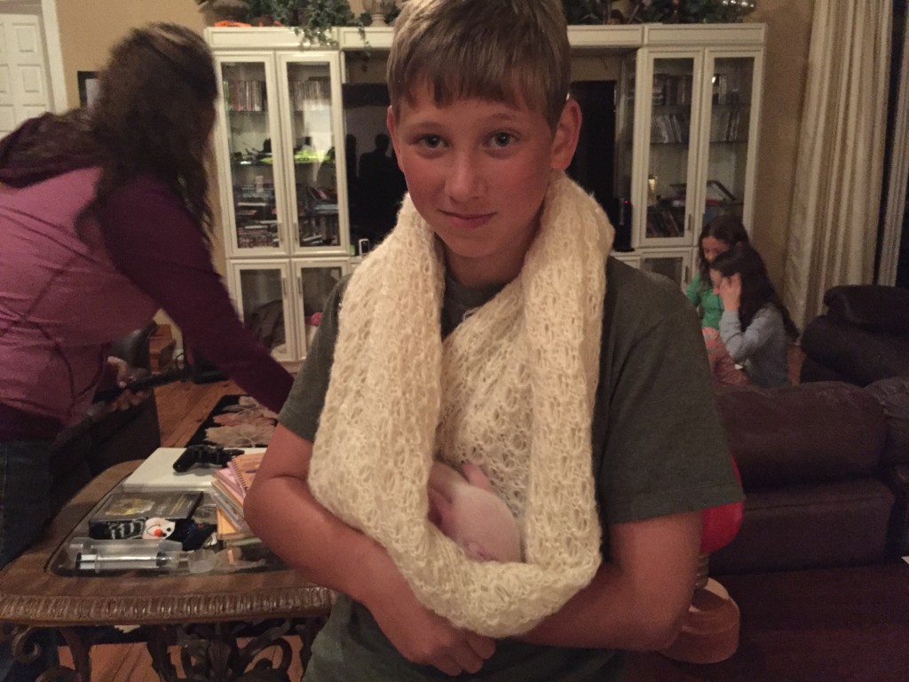 Boy with baby piglet in wool scarf
