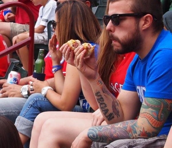 Guy with vegan tatoo eating a meat hot dog