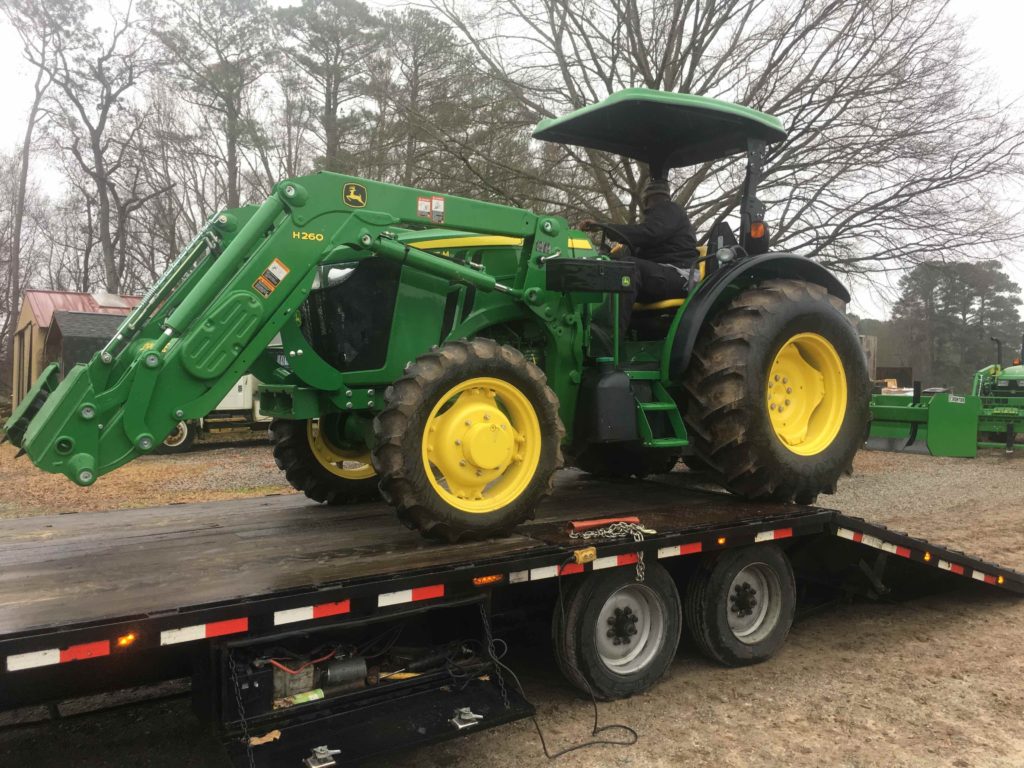 The new tractor, backing off of the delivery trailer in the rain